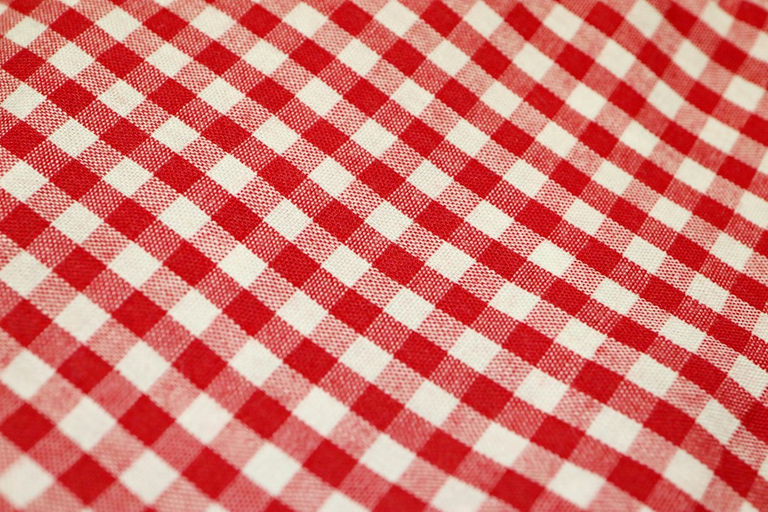 Gros plan sur un tissu de coton à carreaux rouges et blancs, le motif traditionnel du krama cambodgien